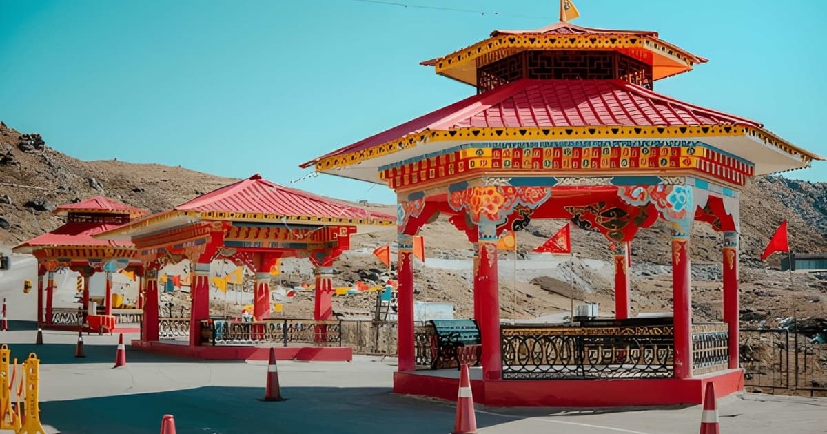 Brightly painted traditional red and yellow pavilions featuring intricate Buddhist architectural details, situated at a scenic high-altitude viewpoint in the Gangtok region of Sikkim.